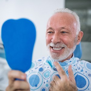 Man looking at his new dental implants in the mirror 
