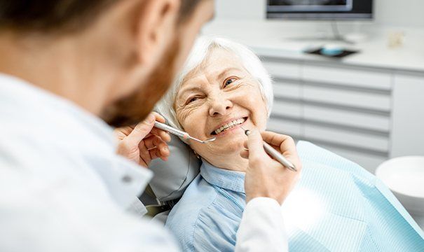 Older woman in dental chair smiling at dentist