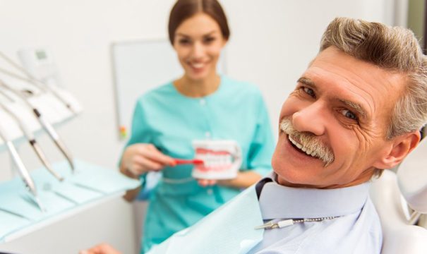 older man at dentist’s office learning about dentures