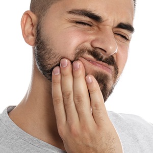 a man holding his jaw due to a dental emergency