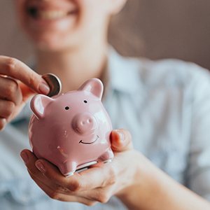 a person putting a coin in a piggy bank