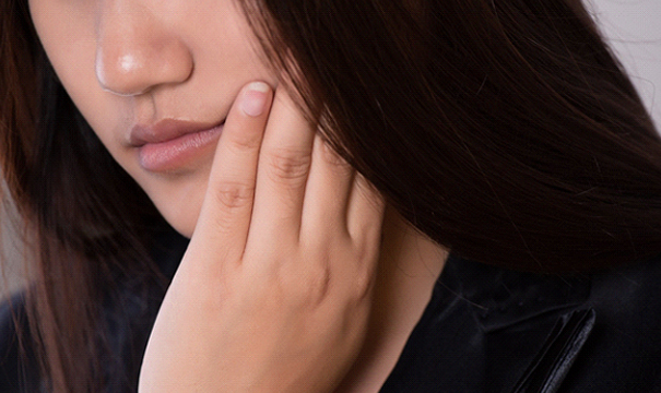 Woman with neutral expression holding hand on cheek