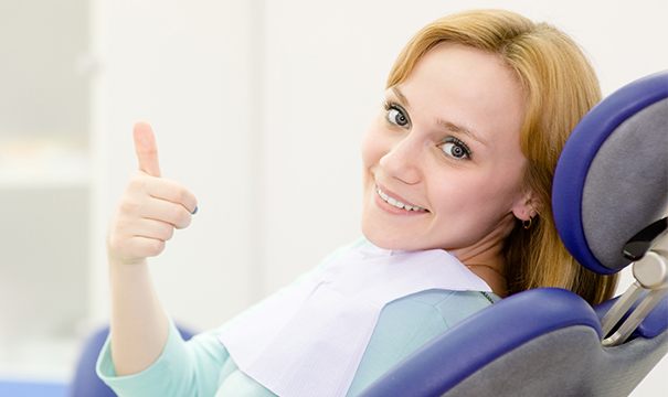 Woman in dental chair giving thumbs up