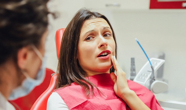 woman holding cheek in the dental chair