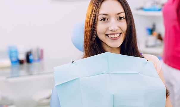 Woman with brown hair sitting in dental chair and smiling