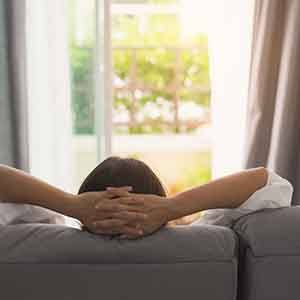 Back of woman resting on couch with hands behind head