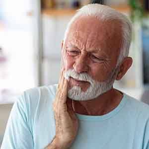 Senior man rubbing his jaw due to discomfort