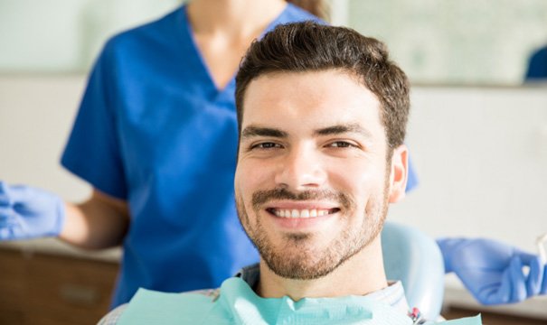 Male dental patient sitting in chair and smiling