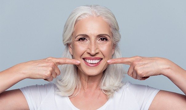 Older woman pointing to her smile