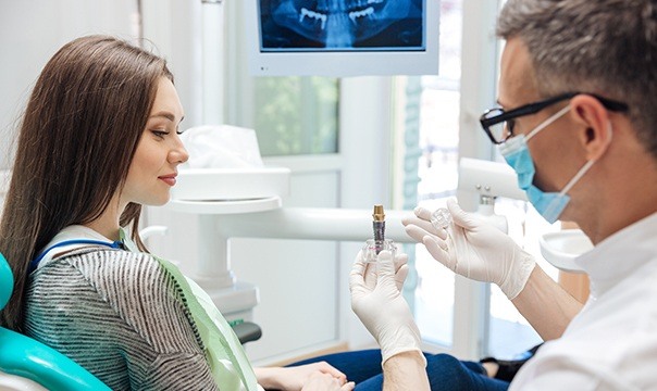 Dentist showing patient dental implant model