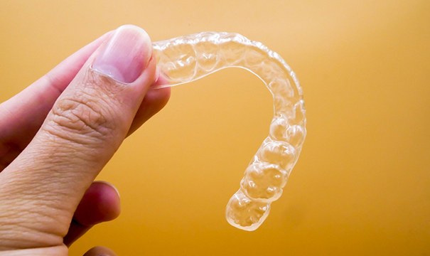 Close up of woman holding Invisalign in Newton
