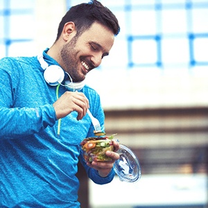 Man in blue shirt eating healthy lunch after working out