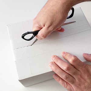 Man using scissors to open white box