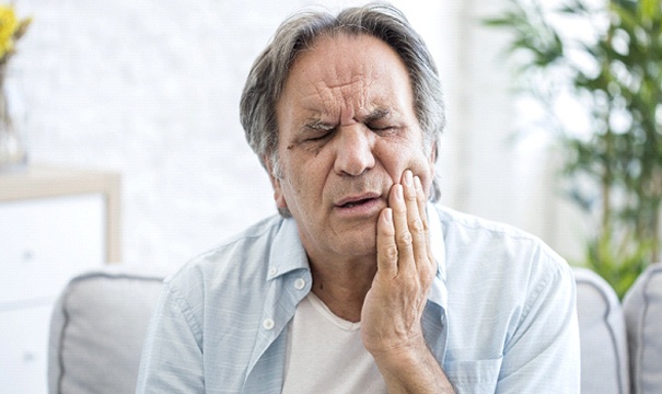 Man with toothache needing tooth extraction in Newton