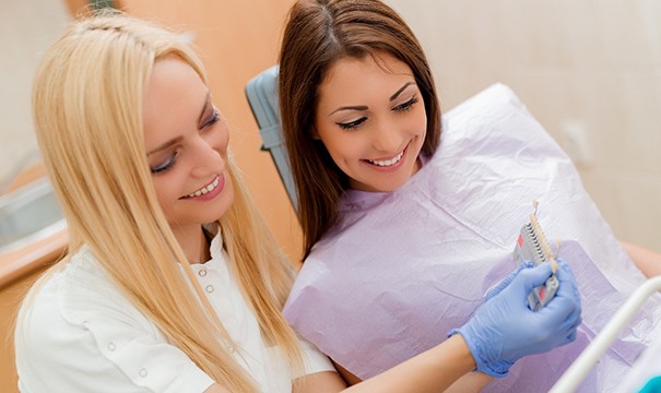 A dentist showing a shade guide to a female patient