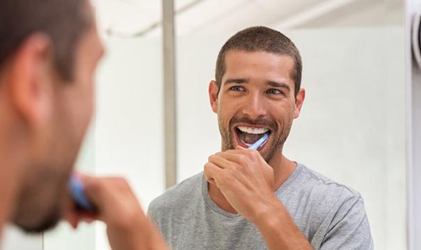 Man brushing his teeth after visiting Newton dentist 