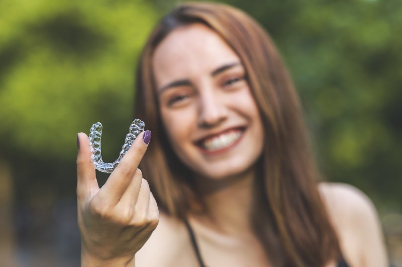 girl smiling holding an Invisalign aligner