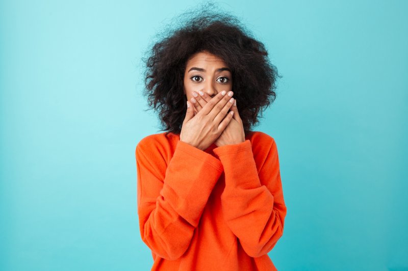 person with shifting teeth covering mouth