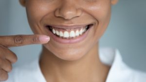 a woman smiling and pointing to her straight smile