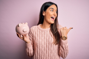 a person smiling and holding a piggy bank