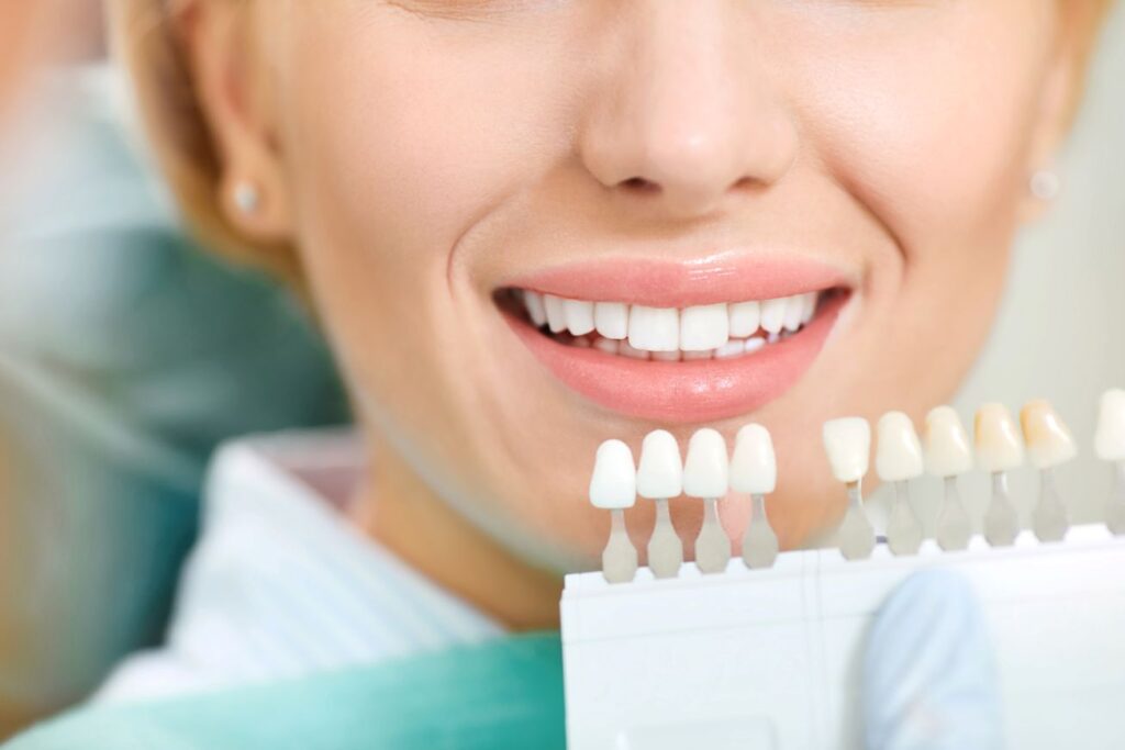 A woman holding a tooth shade indicator at the dentist