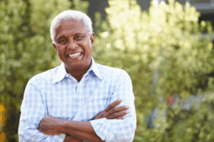 Man smiling outside with plants in background